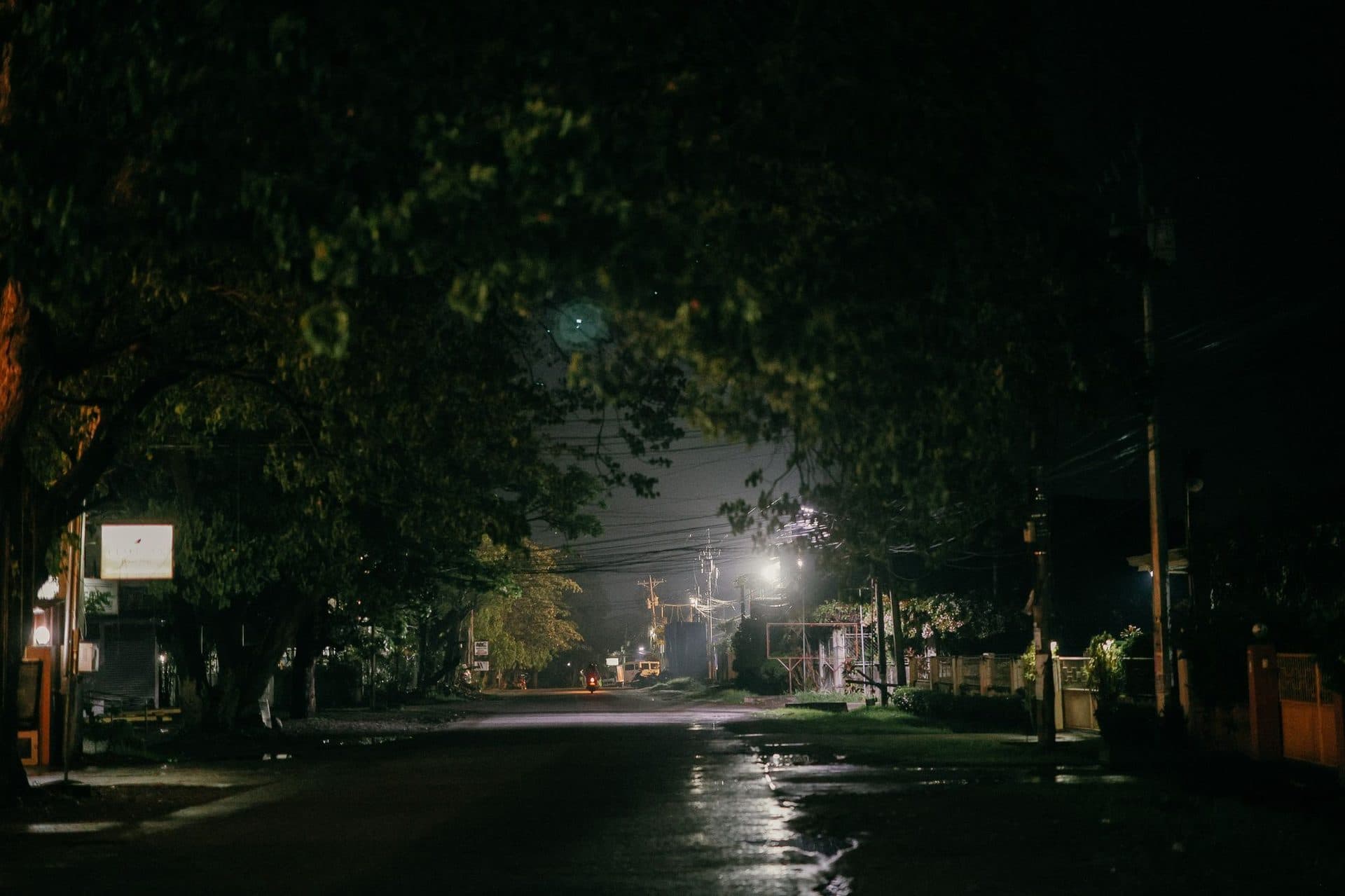 A neighborhood street at night with a pole-mounted street light